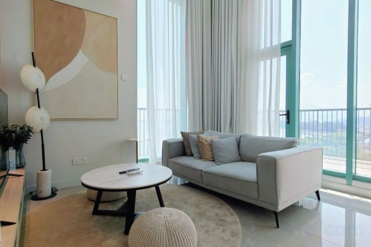 A modern living room with a sofa, a round coffee table, and a large window with curtains.