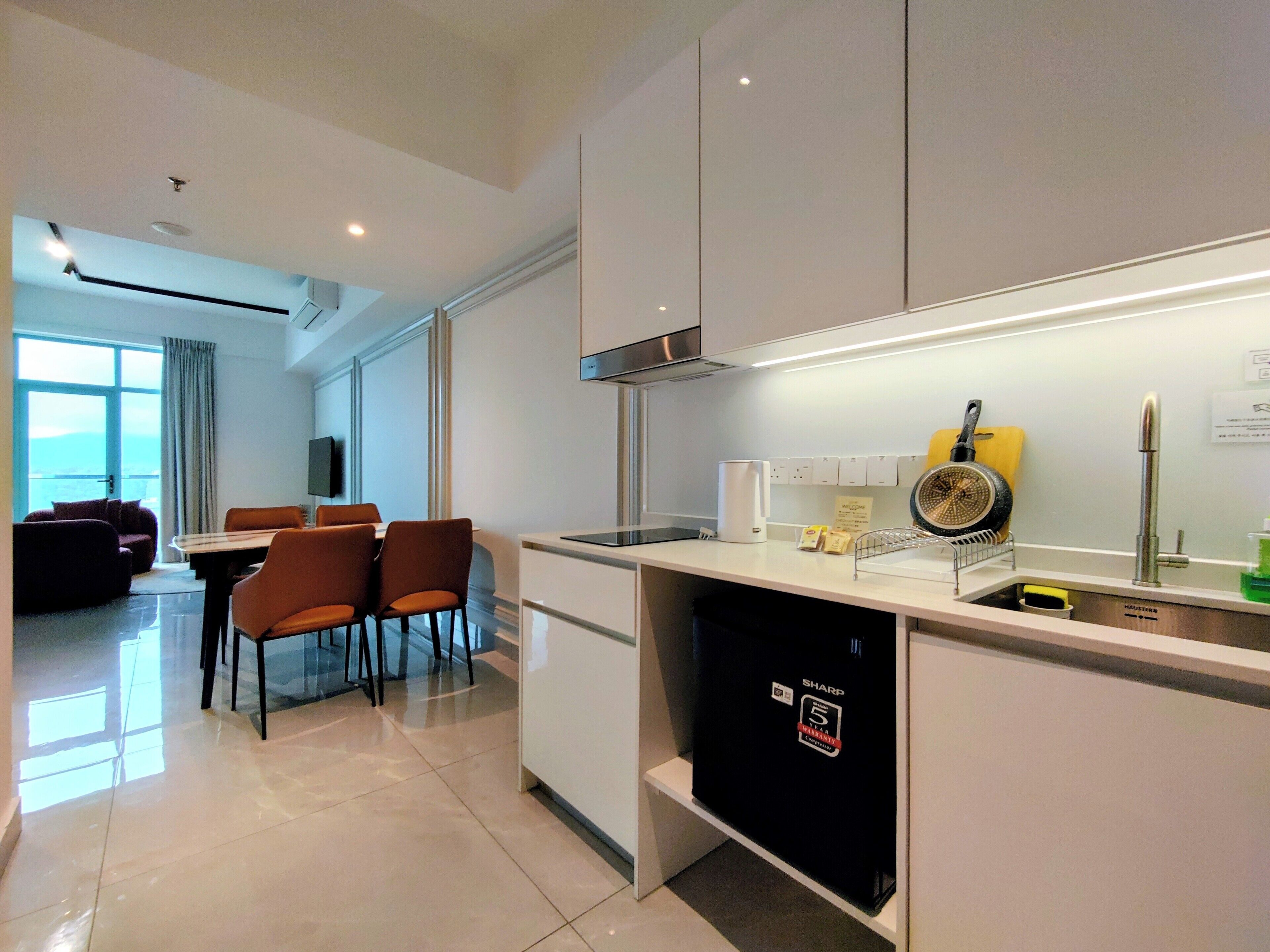 A modern kitchen with a built-in dishwasher, a coffee maker, and a frying pan on the counter.