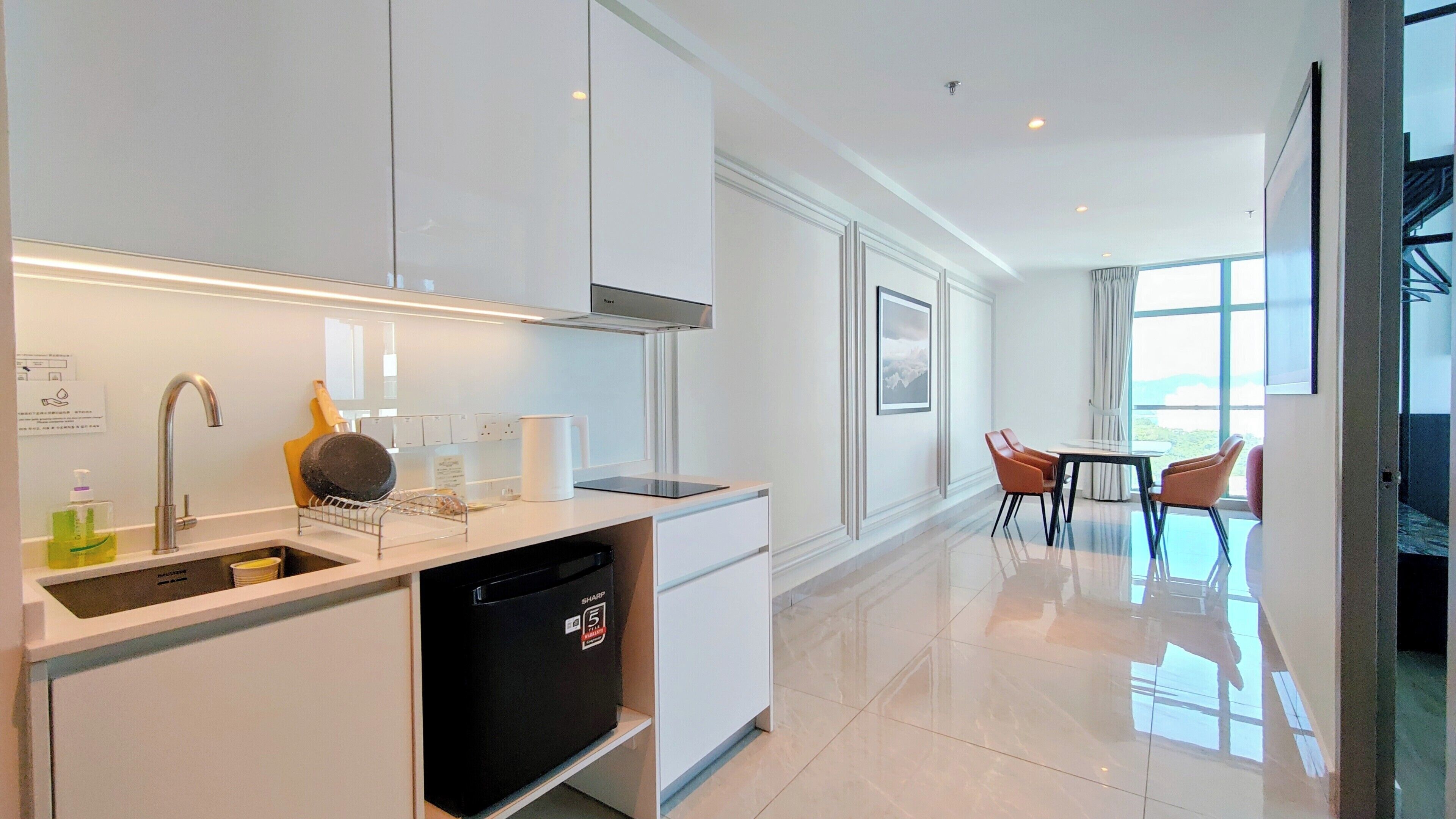 A modern kitchen with a dishwasher, a sink, and a stove. There is a dining area with a table and chairs.