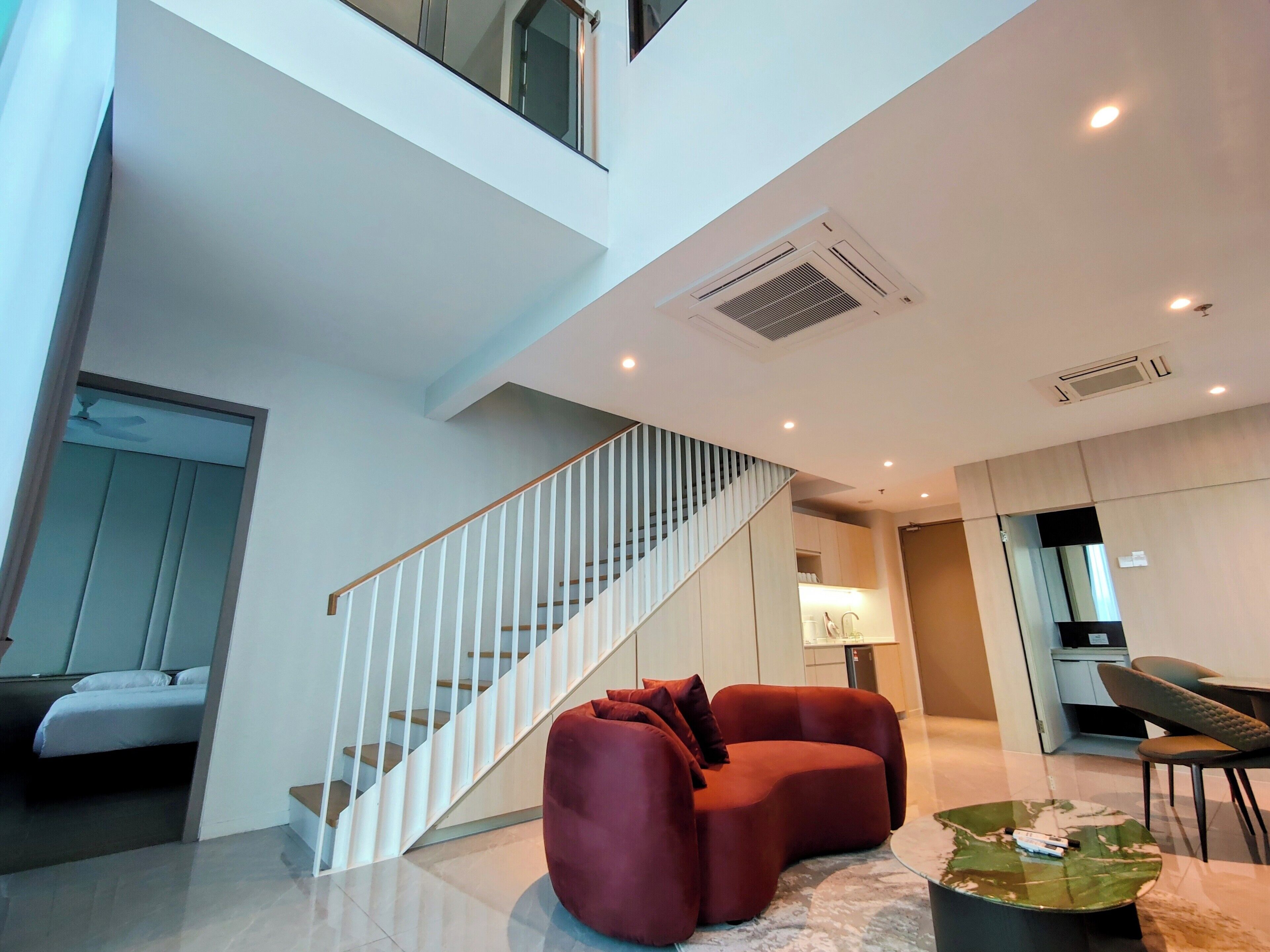 A modern interior with a staircase, a red sofa, and a dining area.