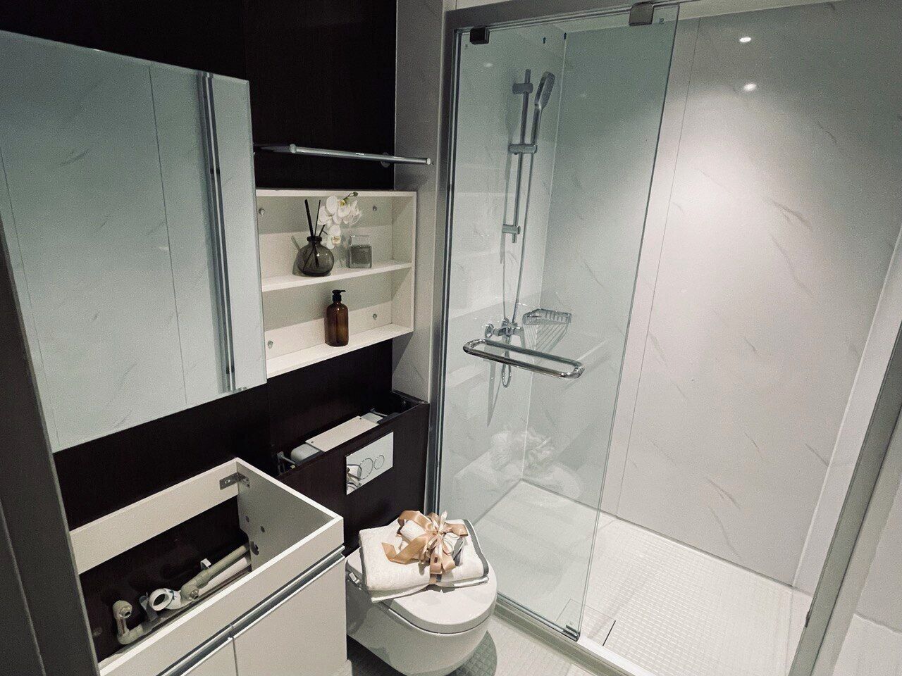 A modern bathroom with a glass-enclosed shower, a toilet, and built-in storage cabinets.