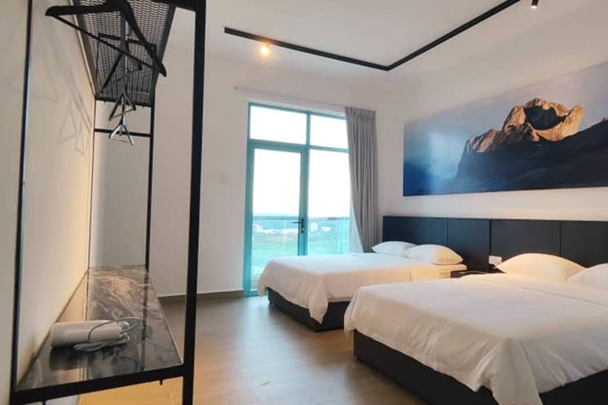 A hotel room with two beds, a large window with a view, and a painting of mountains on the wall.