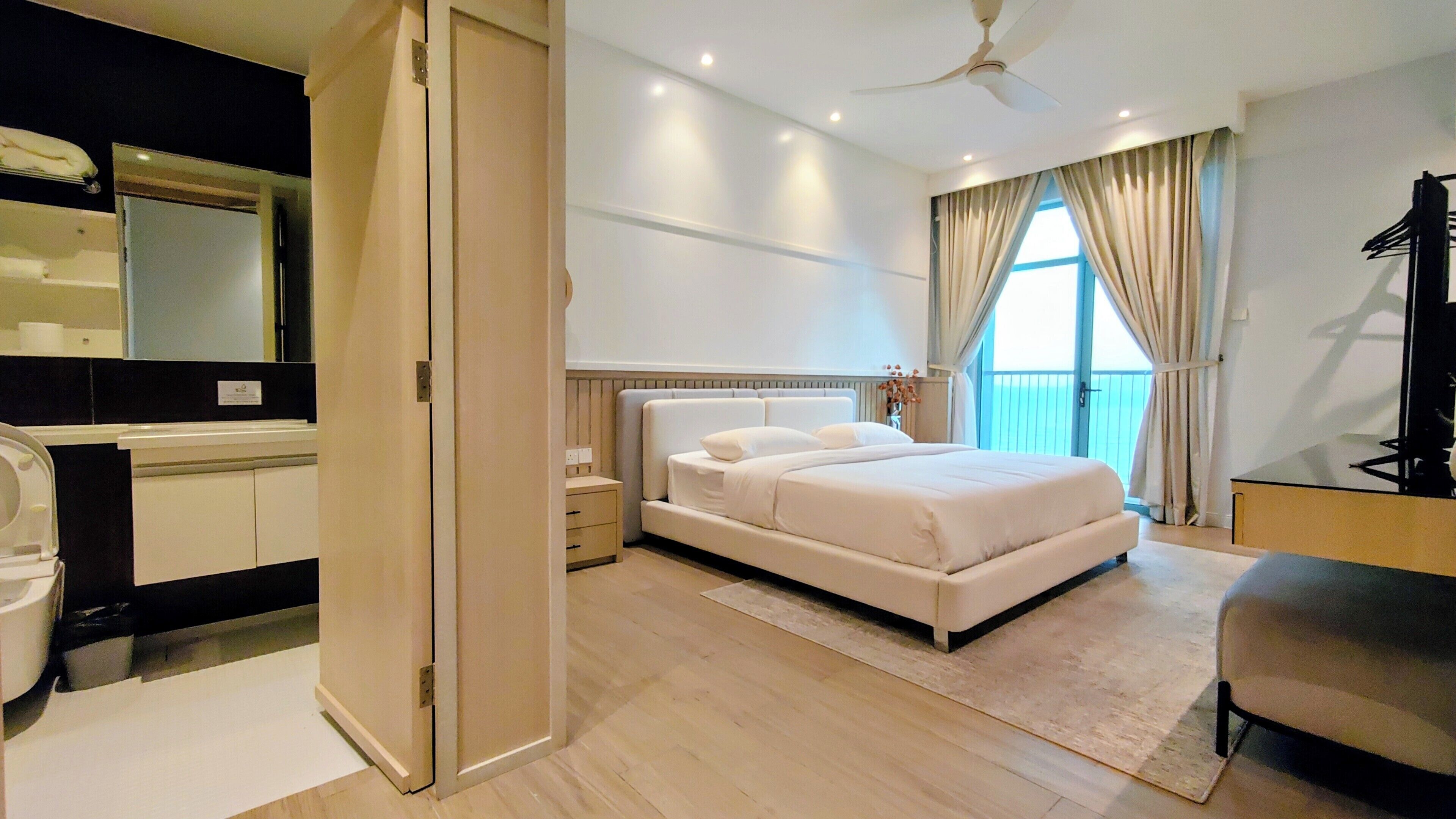 A bedroom with a bed, a ceiling fan, a nightstand, a dresser, a mirror, and a view of the outside.
