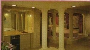 A spa-like room with a large bathtub, a sink, and a mirror. There are pillars and a ceiling with recessed lighting. - Miami Princess Hotel (Miami)