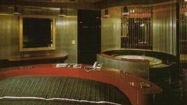 A hotel room with a curved bed, a small desk, and a large window. - Miami Princess Hotel (Miami)