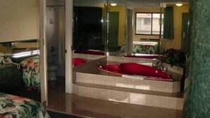 A room with a large mirror, a red sofa, and a small table. - Miami Princess Hotel (Miami)