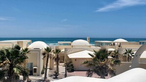Un resort con diversi edifici a cupola bianca, palme e una vista limpida sull'oceano.