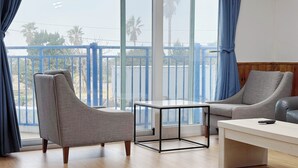 Un salón moderno con balcón, dos sillones grises, una mesita y una mesa de centro de madera.