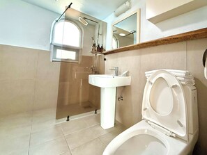 A bathroom with a toilet, sink, and shower. - Sweet Stay (Seogwipo)