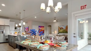A modern kitchen with a dining area set for a meal. - Red Rock Roamin' | Private Pool, & Hot Tub | Resort Amenities | Sleeps 21 (Hurricane)