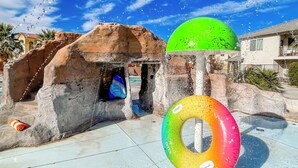 A water play area with a rock structure, a colorful inflatable ring, and a clear blue sky. - Red Rock Roamin' | Private Pool, & Hot Tub | Resort Amenities | Sleeps 21 (Hurricane)