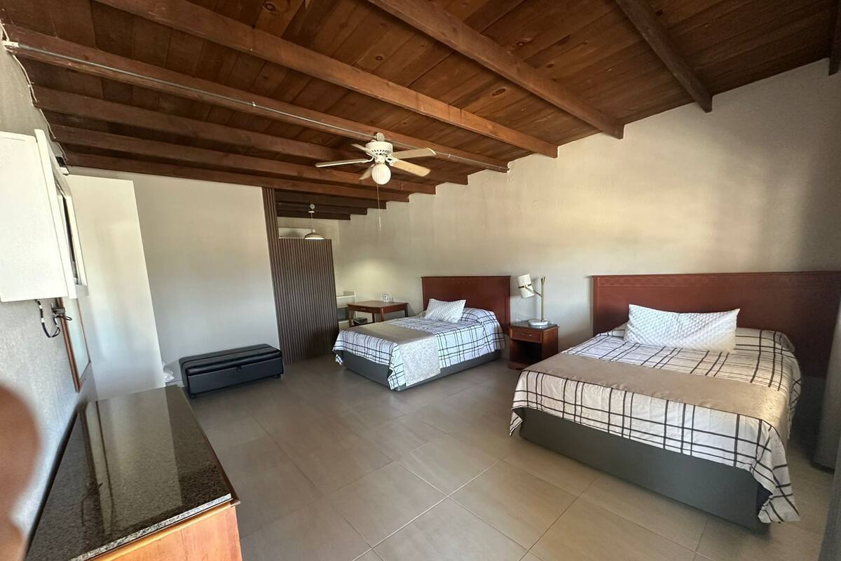 A bedroom with two beds, a ceiling fan, a desk, and a wardrobe.