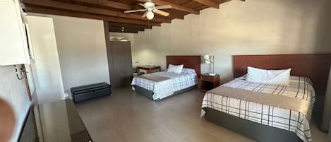 A bedroom with two beds, a ceiling fan, a desk, and a wardrobe.