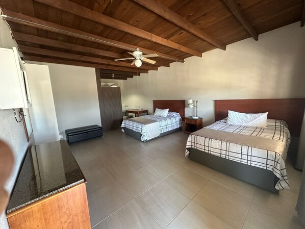 A bedroom with two beds, a ceiling fan, a desk, and a wardrobe. - Hotel Villa Vitta (Bahia de los Angeles)