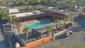 Villa Vetto, a hotel with a swimming pool, surrounded by palm trees and a parking area. - Hotel Villa Vitta (Bahia de los Angeles)