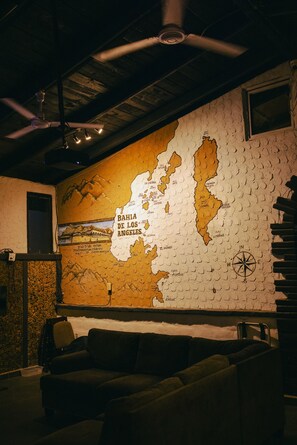 Una habitación con un mapa de las Bahamas en la pared, un ventilador de techo y un sofá.