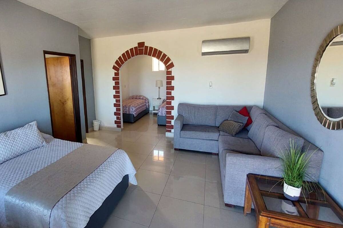 A modern living room with a sofa, a bed, and a small table with a plant.