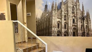 Una escalera con barandilla de metal que lleva a un cuarto con un gran mural de una catedral.
