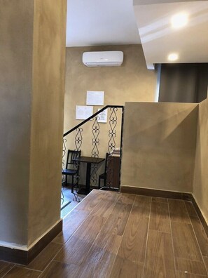 A modern interior with a staircase, wooden flooring, and a wall-mounted air conditioner.