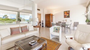 Ein modernes Wohnzimmer mit einer Couch, Sesseln, einem Couchtisch und einem Essbereich mit Stühlen und einem Tisch.