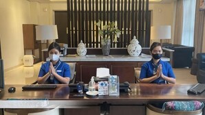 A reception desk with two staff members, a vase, a lamp, and a plant in the background. - M Hotel Sorong Managed by East Season (Sorong)