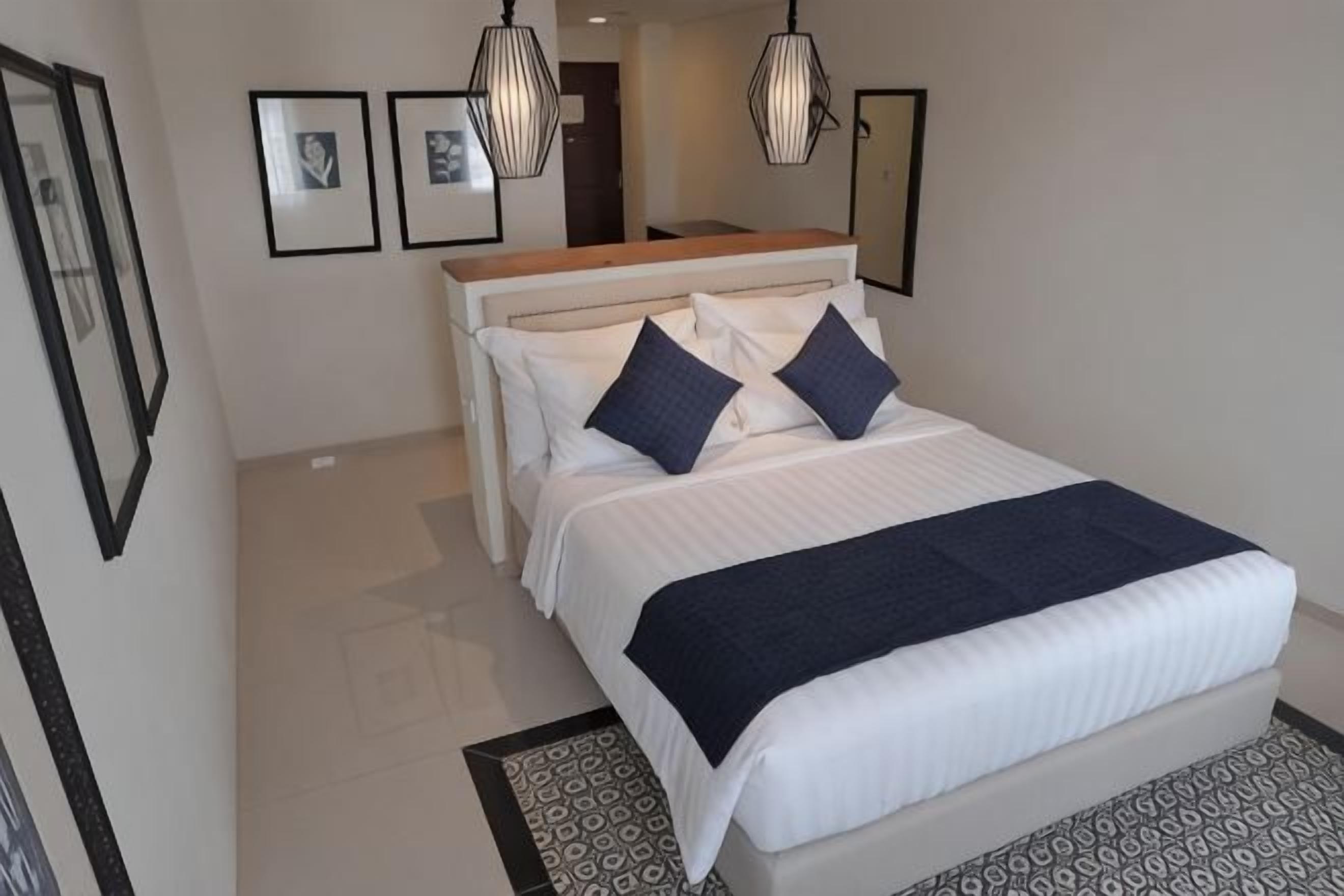 Ein Schlafzimmer mit einem Bett, zwei Kissen, einem Nachttisch und einem gemusterten Teppich.