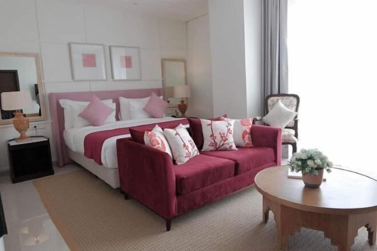 A hotel room with a bed, a sofa, a round table, and a small side table.