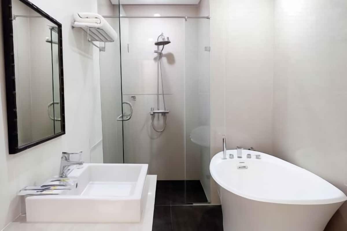 A modern bathroom with a freestanding bathtub, a large mirror, and a glass-enclosed shower area.