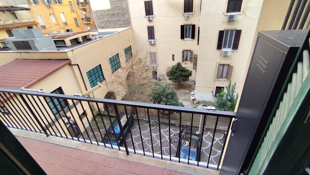 Balcón con vista a un patio interior, donde se ve una bicicleta y un coche estacionados.