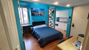 Un dormitorio pequeño con cama, escritorio y kitchenette.
