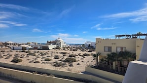 Wüstenlandschaft mit Gebäuden, darunter eine weiße Kuppelstruktur und ein modernes Gebäude mit einem Balkon.