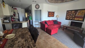 Ein Wohnzimmer mit einem roten Sofa, einem Fernseher und einem Essbereich mit Tisch und Stühlen.