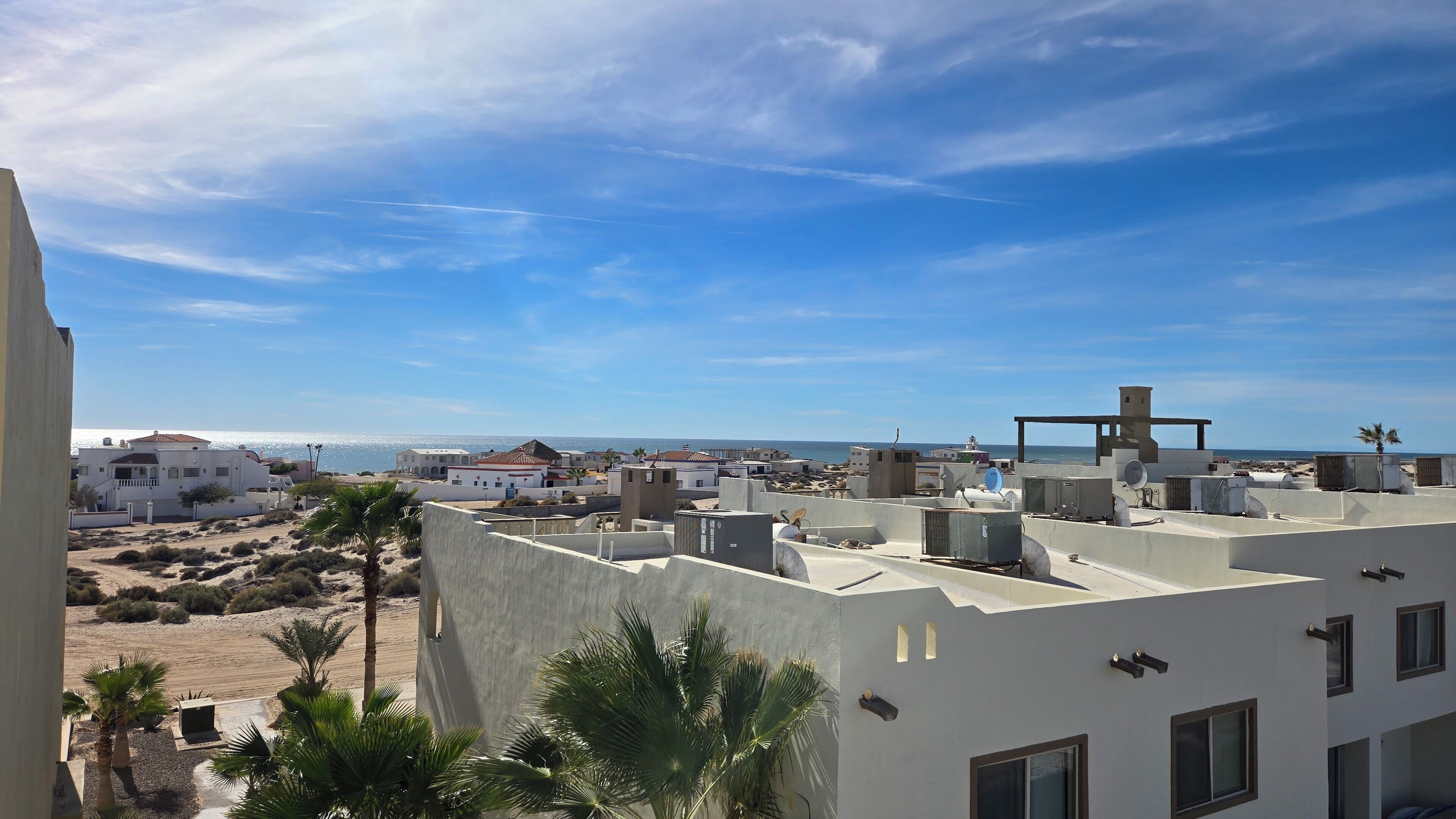 Zona residencial costera con edificios, una playa y cielo despejado.