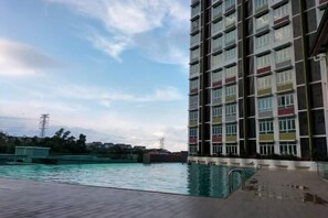 Um edifício alto com várias varandas com vista para uma área de piscina.