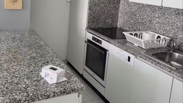 Una cucina moderna con mobili bianchi, un piano di lavoro in granito, forno integrato, lavastoviglie e schienale in granito.