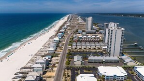 Vista aérea de una zona costera con playa, carretera y edificios, incluyendo un hotel alto.