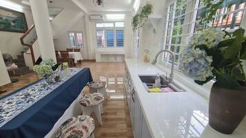 A modern kitchen with a long counter, a sink, and a window with a view. There is a dining area with a table and chairs.