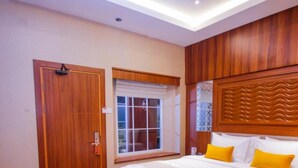 Een hotelkamer met een groot bed, een houten deur, een raam en een geruit vloertje.