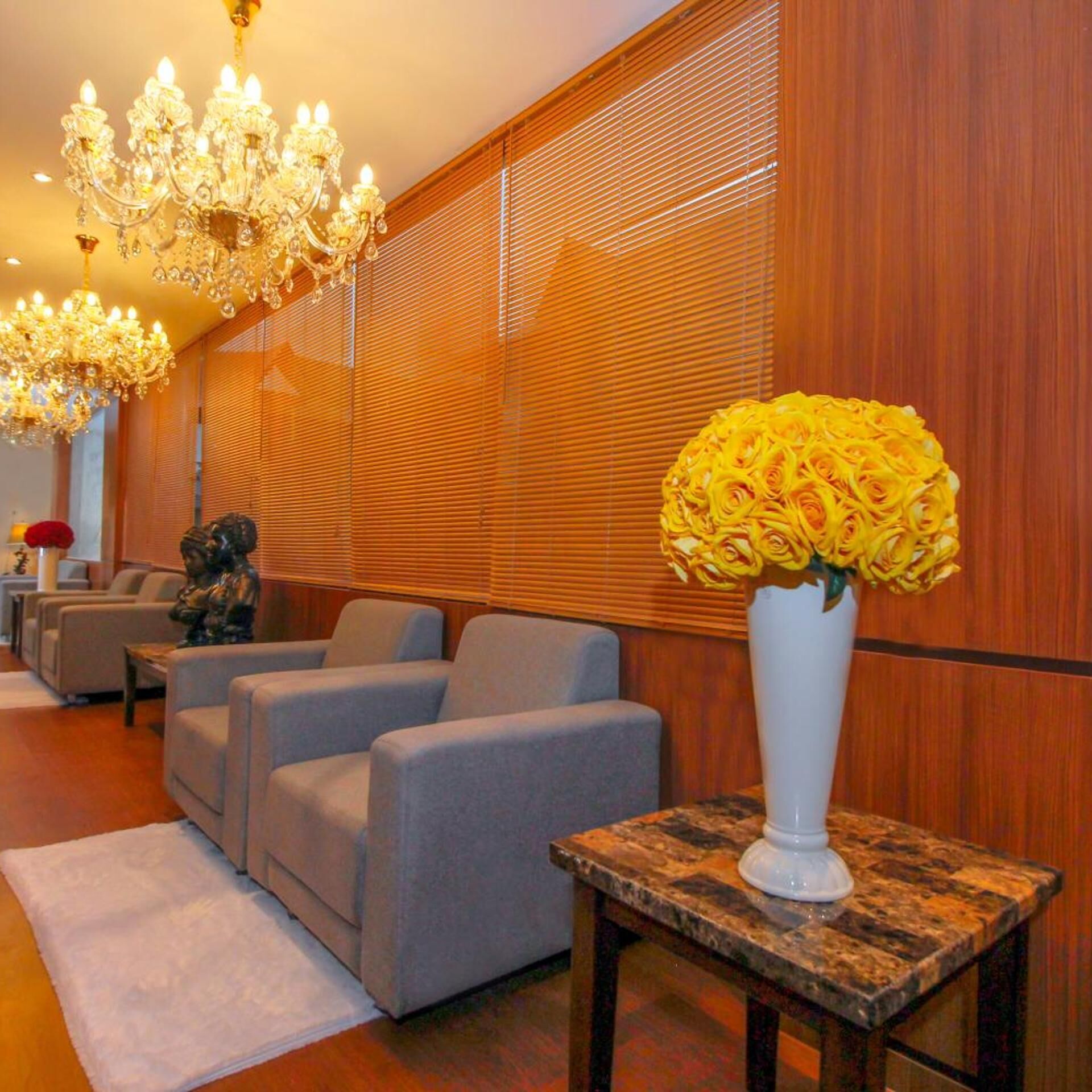 En hotellobby med en kristallkrona, soffor, en staty och en vas med blommor.