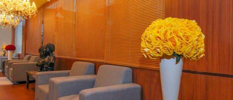 En hotellobby med en kristallkrona, soffor, en staty och en vas med blommor.