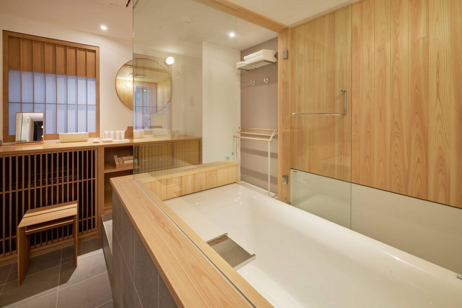 A modern bathroom with a wooden vanity, a glass shower enclosure, and a large mirror.