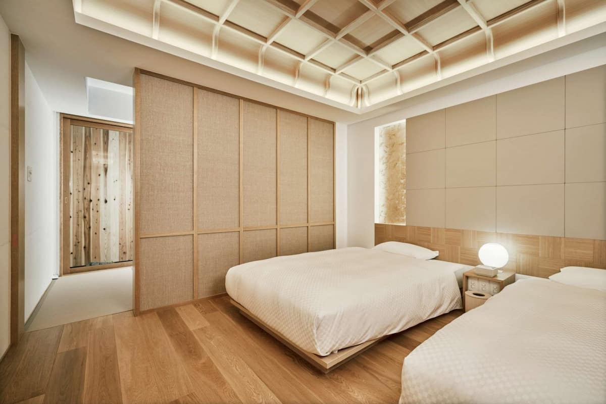 A modern bedroom with two beds, a wooden wardrobe, and a skylight ceiling.