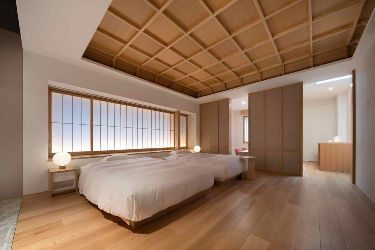 A spacious bedroom with a large bed, a walk-in closet, and a view through a sliding door.