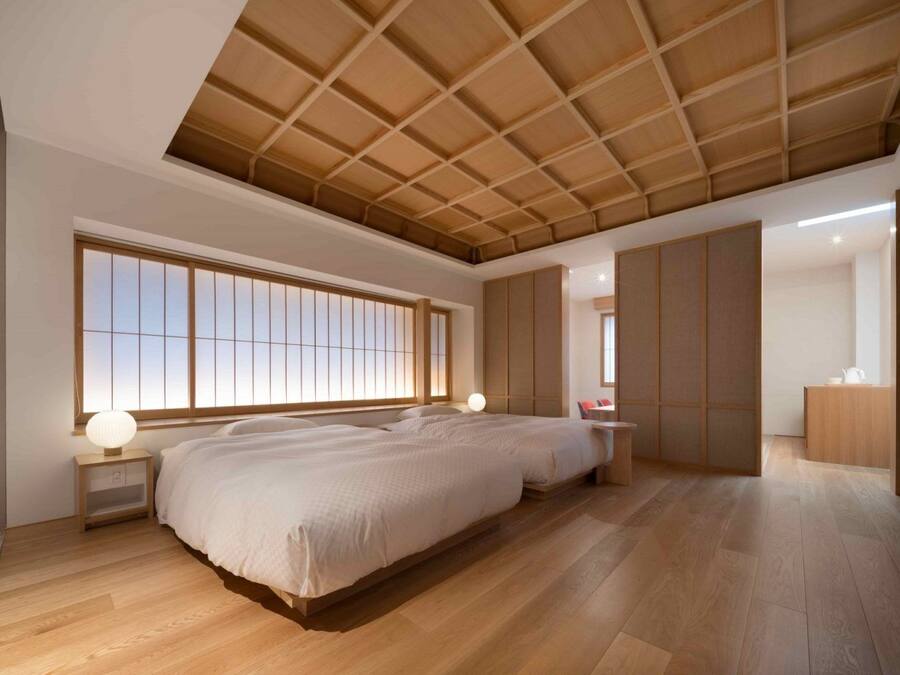 A spacious bedroom with a large bed, a walk-in closet, and a view through a sliding door.