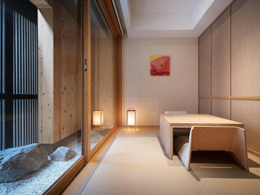 Una habitación japonesa tradicional con suelo de tatami, una mesa de madera baja, puertas correderas shoji y dos faroles colgantes.