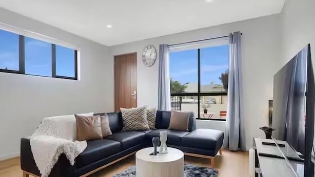 Ein modernes Wohnzimmer mit einem schwarzen Sofa, einem weißen Couchtisch und einem Flachbildfernseher.