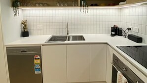 A modern kitchen with wooden cabinets, a stainless steel sink, and a dishwasher. - HENLEY BEACH:WHERE RELAXATION MEETS ADVENTURE BY THE SEA-NEAR AIRPORT (Henley Beach South)