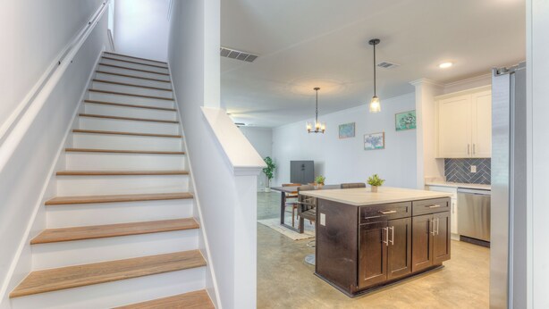 Une cuisine moderne avec des meubles en bois, un îlot central et un coin repas comprenant une table et des chaises.