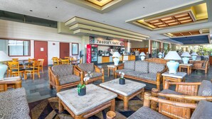 Een ruime lobby met diverse zithoeken, een Coca-Cola automaat en een bord met Jagger's Cafe.