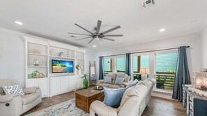 A living room with a sofa, coffee table, TV, and a ceiling fan.